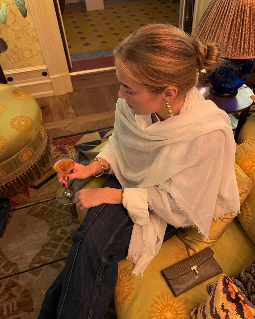 The Air Cashmere Stole in White, worn loose over a white shirt, seated indoors