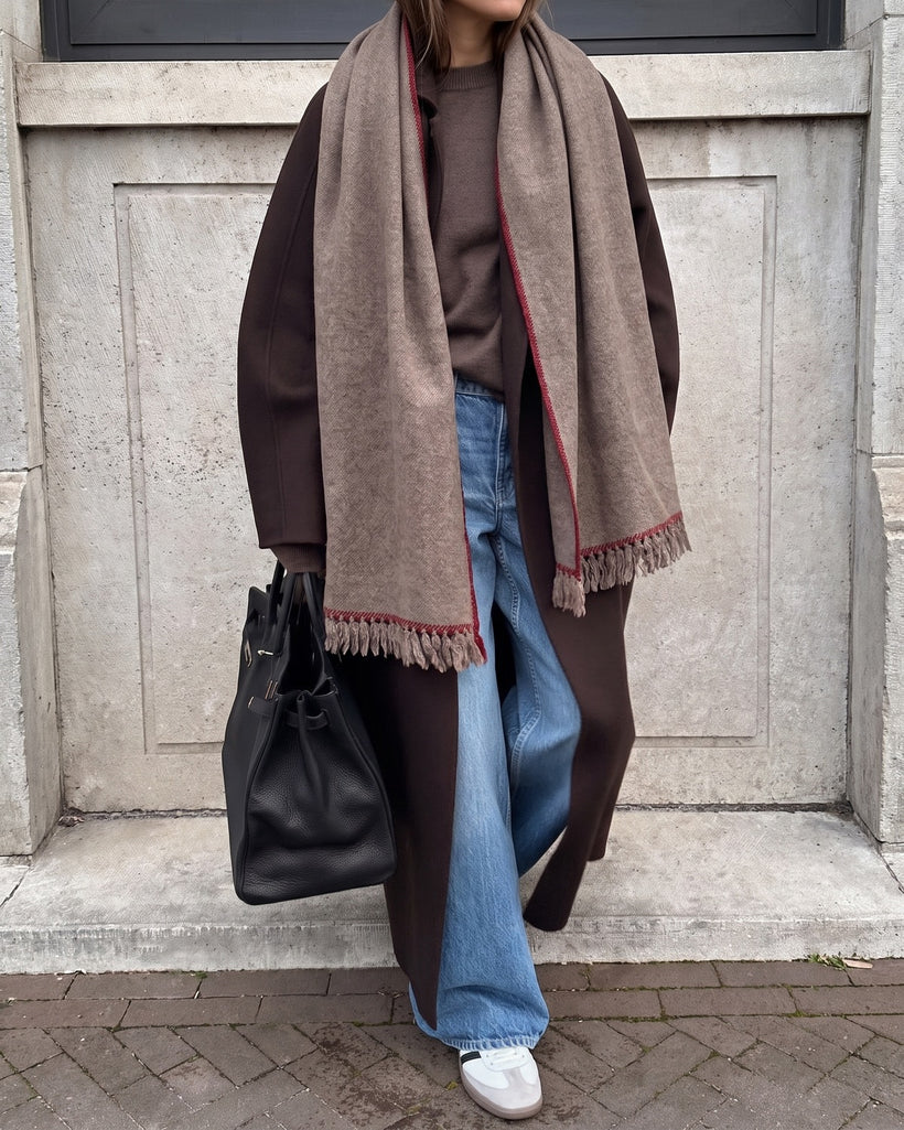 The Hohhot Heritage Wool Wrap in Raw, worn hanging long over a brown coat with jeans