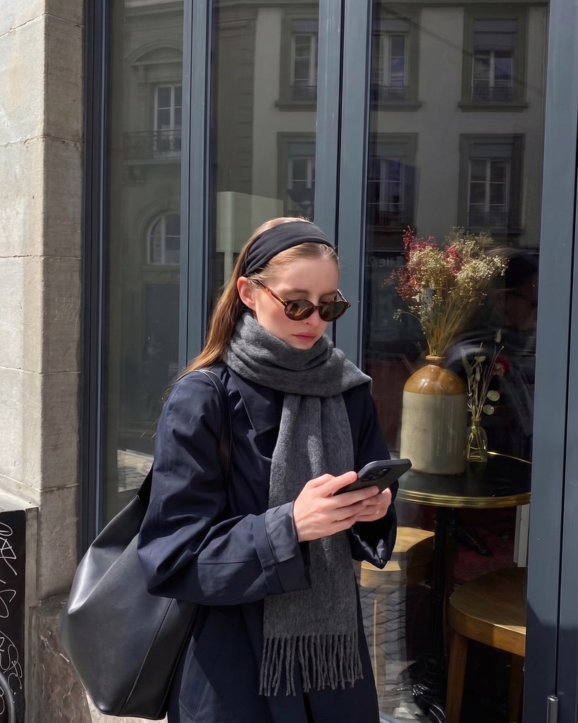 The Slim Wool Scarf in Dark Grey, worn hanging long over a navy coat