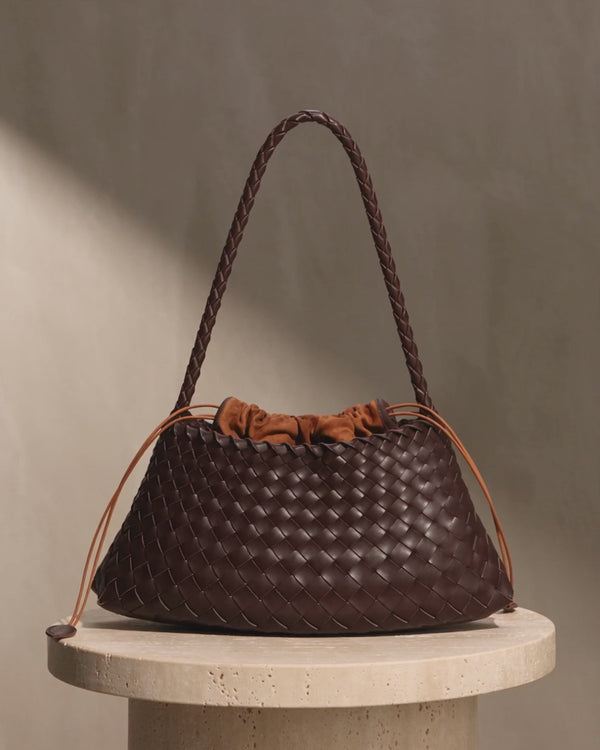 The Ravello Woven Leather Shoulder Bag turning on a stone plinth