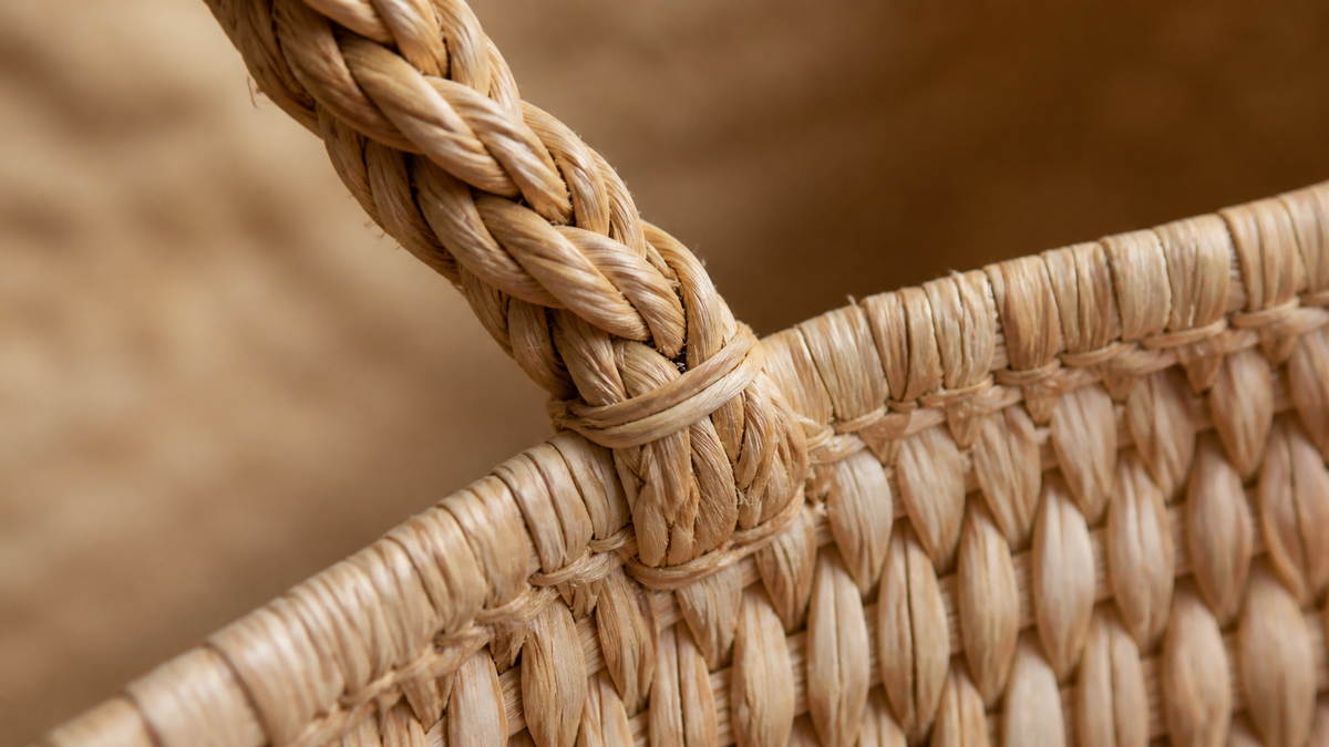 Macro close-up of a braided rope handle joined to the woven rim of a natural raffia bag