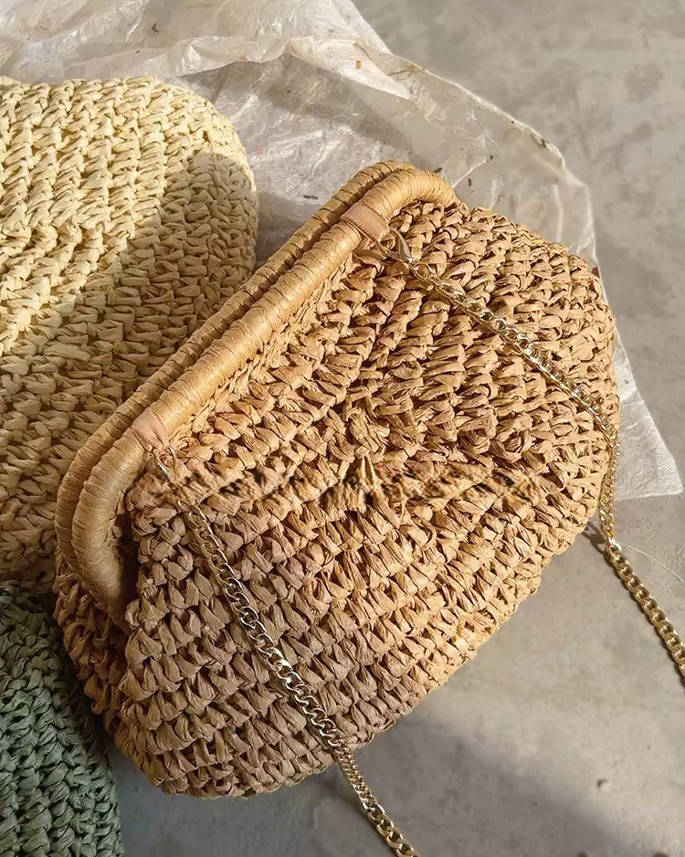 Camel straw bag with brass chain catching evening light — lifestyle shot