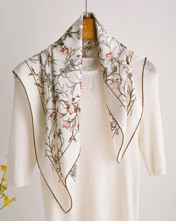 Flat lay of folded scarf showing depth of hand-painted florals across cream base