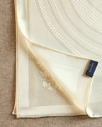 Wildfool solid ivory silk scarf knotted at neck over black top showing gravity drape