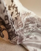Detail of black rose and peony lace pattern trailing across cream sheer silk — asymmetric layout
