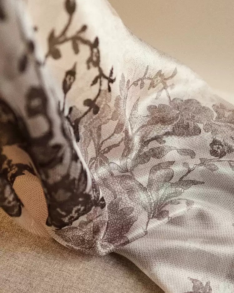 Detail of black rose and peony lace pattern trailing across cream sheer silk — asymmetric layout