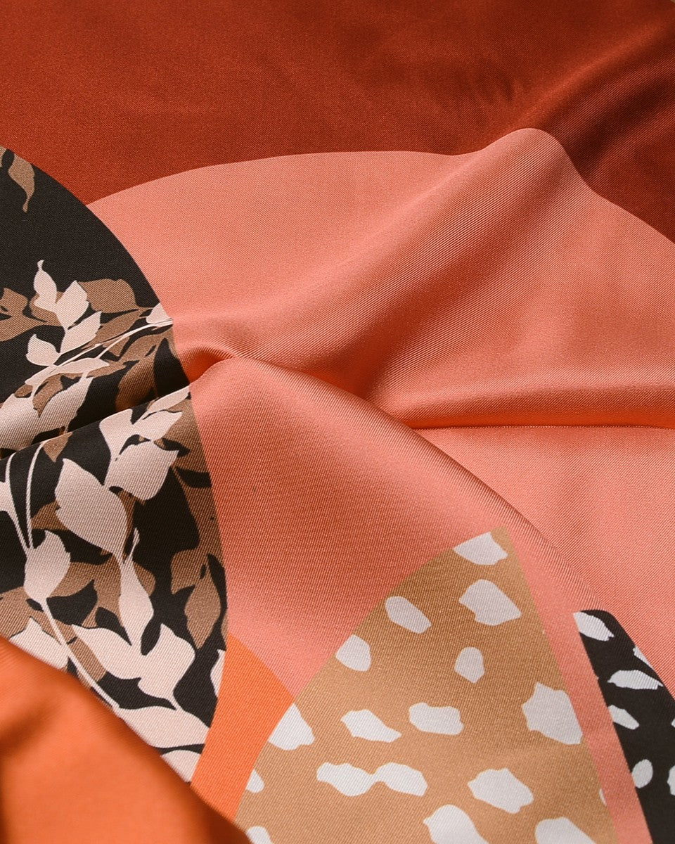 Flat lay of folded geometric scarf showing full composition of mustard fan, black blocks, and leaf silhouettes