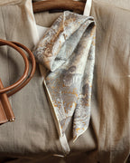 Wildfool silk wool reversible scarf showing gold tropical botanical side — flat lay on linen