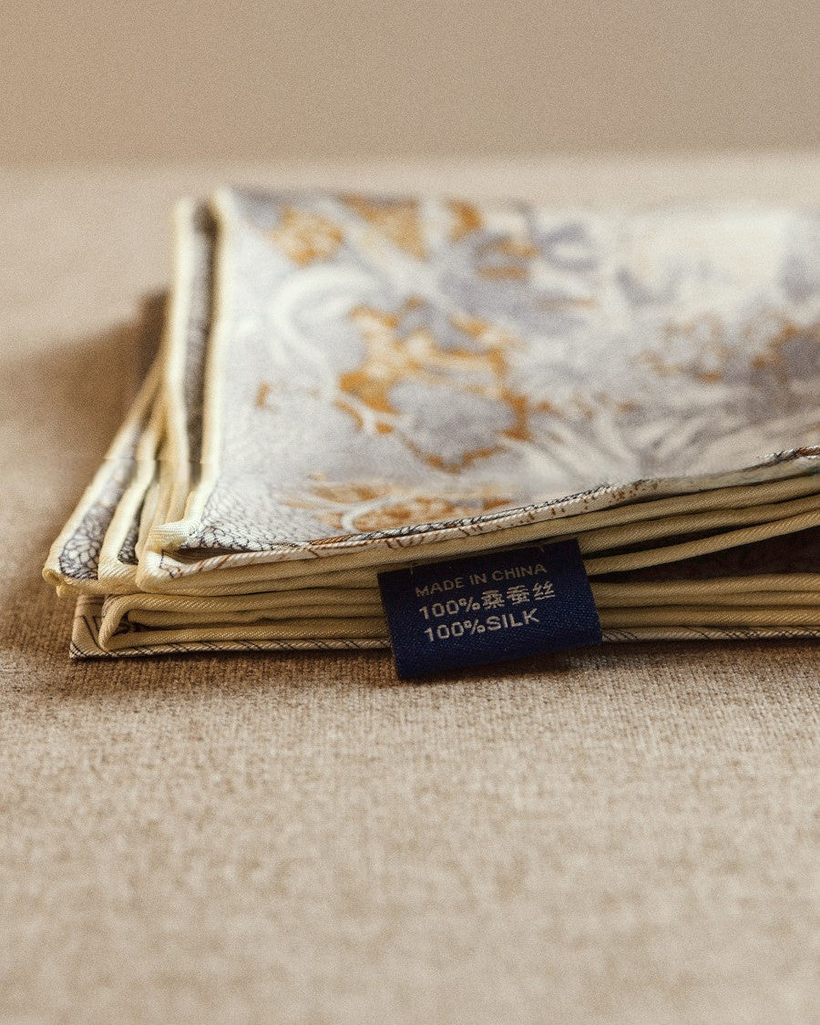 Wildfool reversible scarf draped over shoulder showing gold-amber palm frond and fern detail
