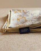 Wildfool reversible scarf draped over shoulder showing gold-amber palm frond and fern detail