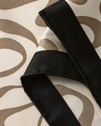 Cream silk scarf tied loosely at neck showing deep navy border and abstract movement