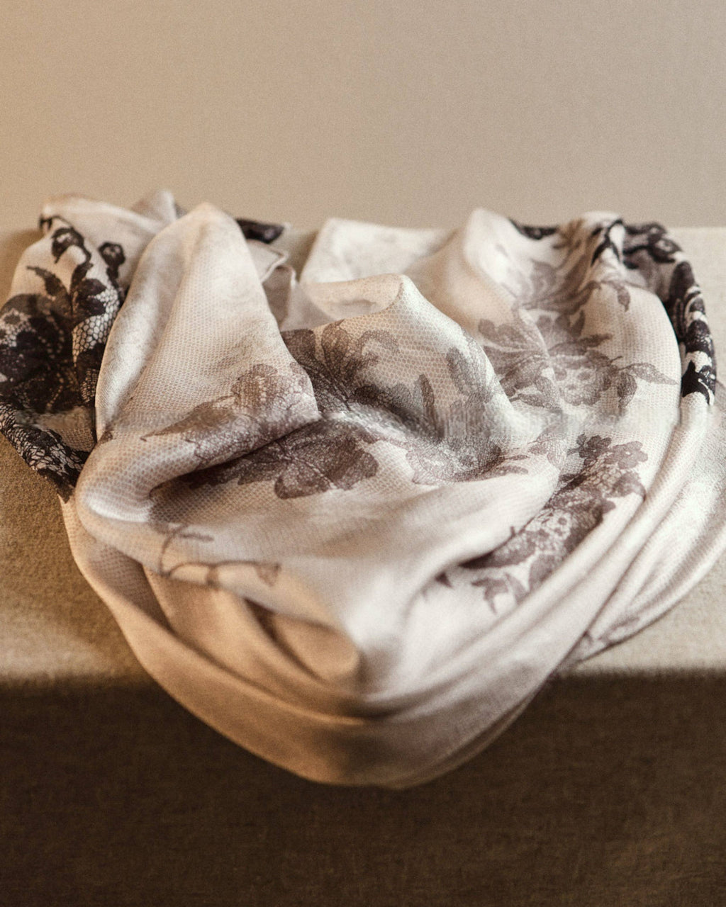 Wildfool lace print silk scarf draped over bare shoulders showing translucent light-through effect