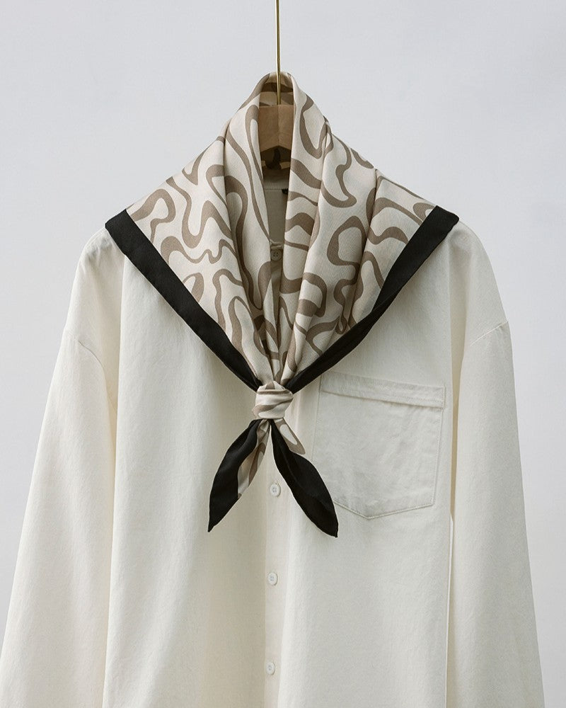 Flat lay of folded scarf showing continuous flow of organic lines and hand-rolled edge detail