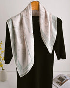 Overhead shot of folded scarf showing delicate equestrian geometry woven throughout