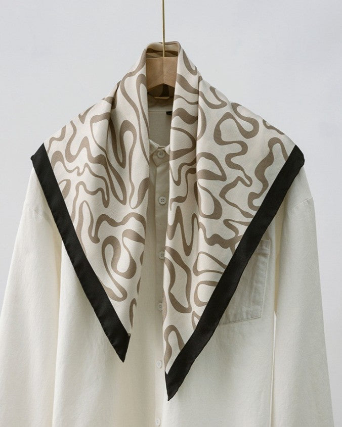 Detail of hand-rolled edge and warm brown plus camel abstract pattern against cream twill base
