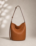 The Lecce Woven Bucket in cognac, front view hanging by its adjustable strap