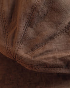 Macro close-up of the washed linen weave and topstitched panel seams on the Wildfool Docker Cap in Espresso