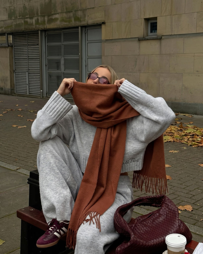 The Dune 100% Cashmere Scarf in Bronze, worn pulled up over the nose with a grey knit set