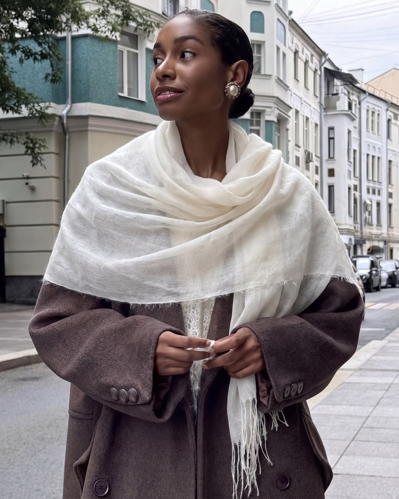The Air Cashmere Stole in White, worn loose over a brown blazer on a city street