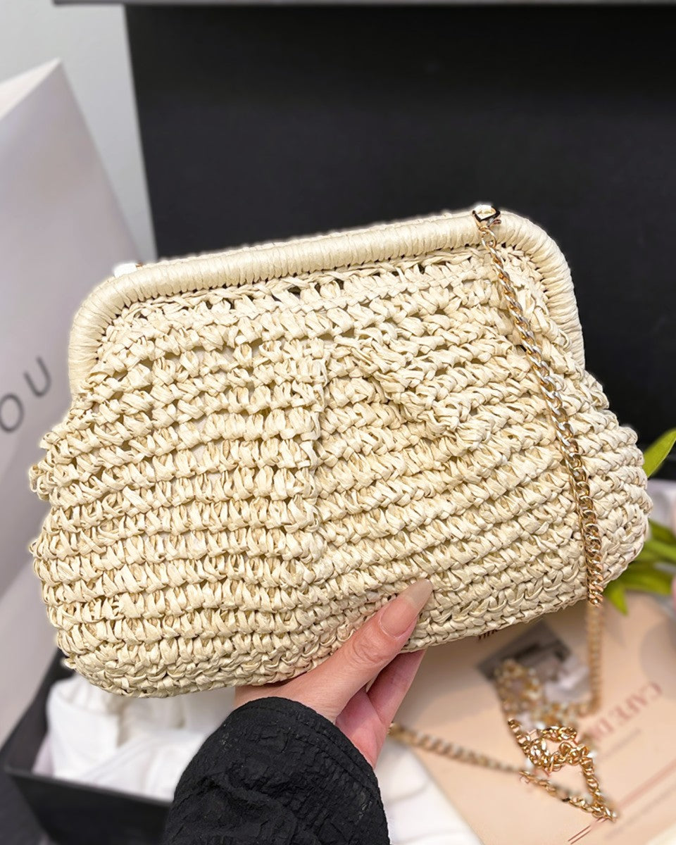 Camel straw bag with brass chain catching evening light — lifestyle shot
