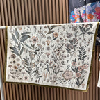 Wildfool botanical specimen scarf draped over blazer shoulder showing gray-green and pink-purple plants