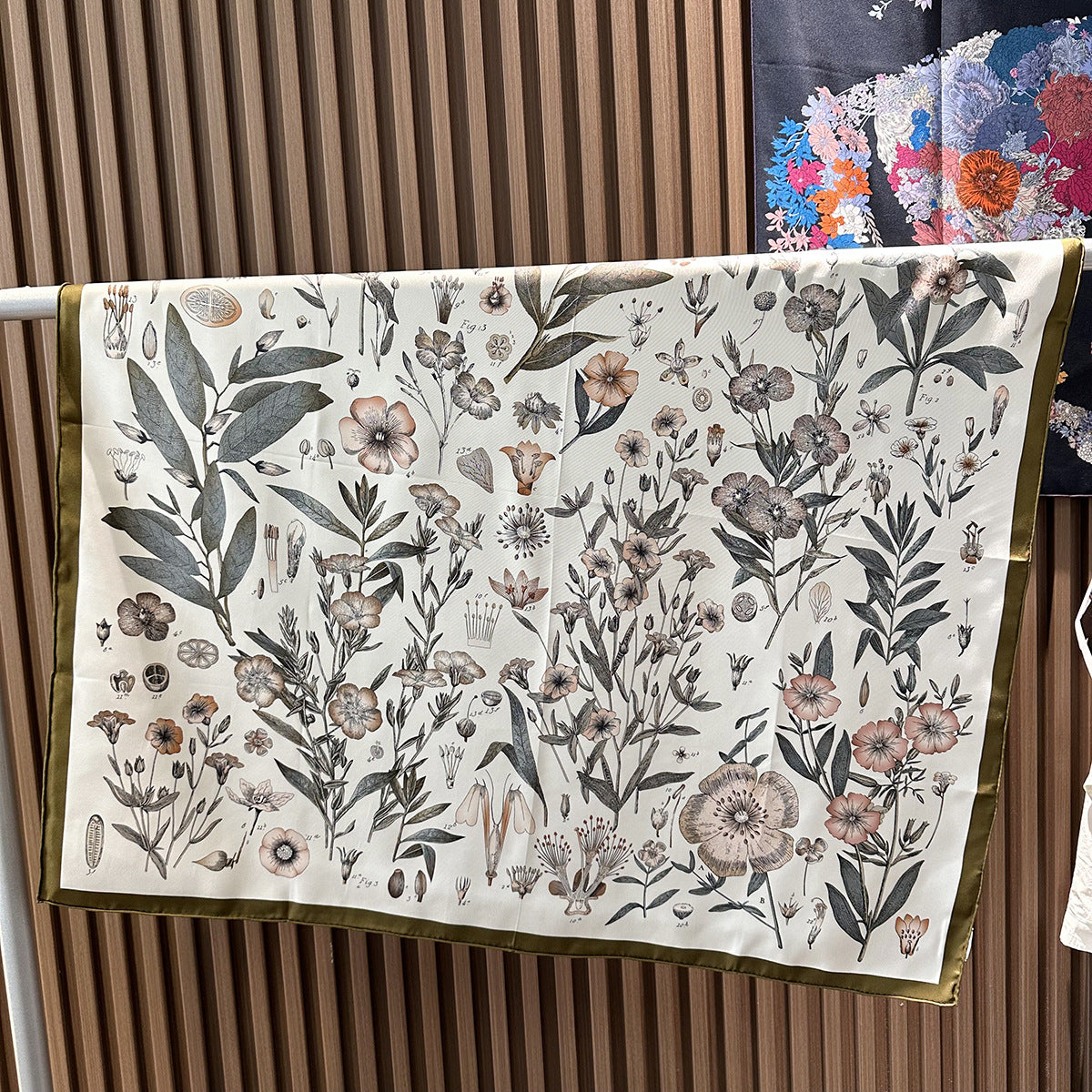 Wildfool botanical specimen scarf draped over blazer shoulder showing gray-green and pink-purple plants