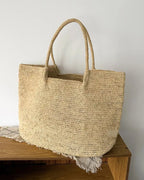 The Florence hand-woven raffia tote styled on natural linen and oak shelf