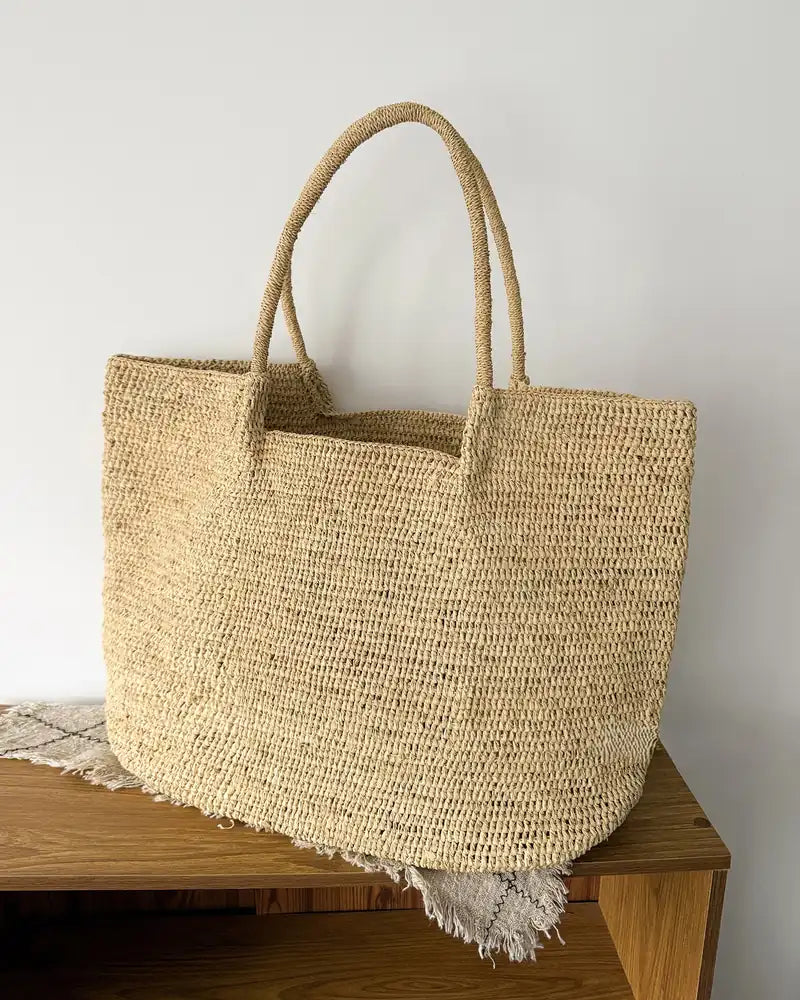 The Florence hand-woven raffia tote styled on natural linen and oak shelf