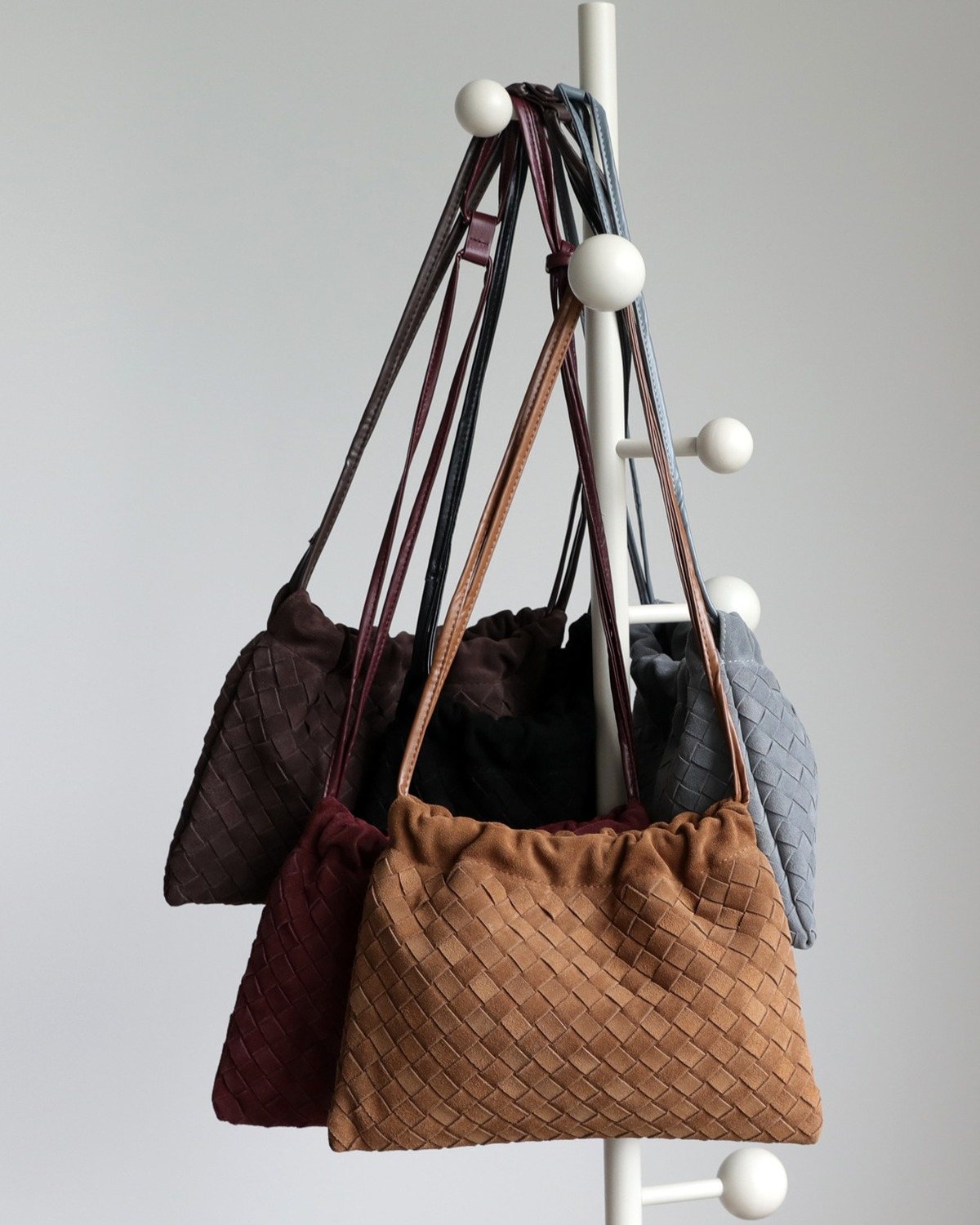 Wildfool The Mantova Drawstring Pouch, all five colours hanging on a coat stand