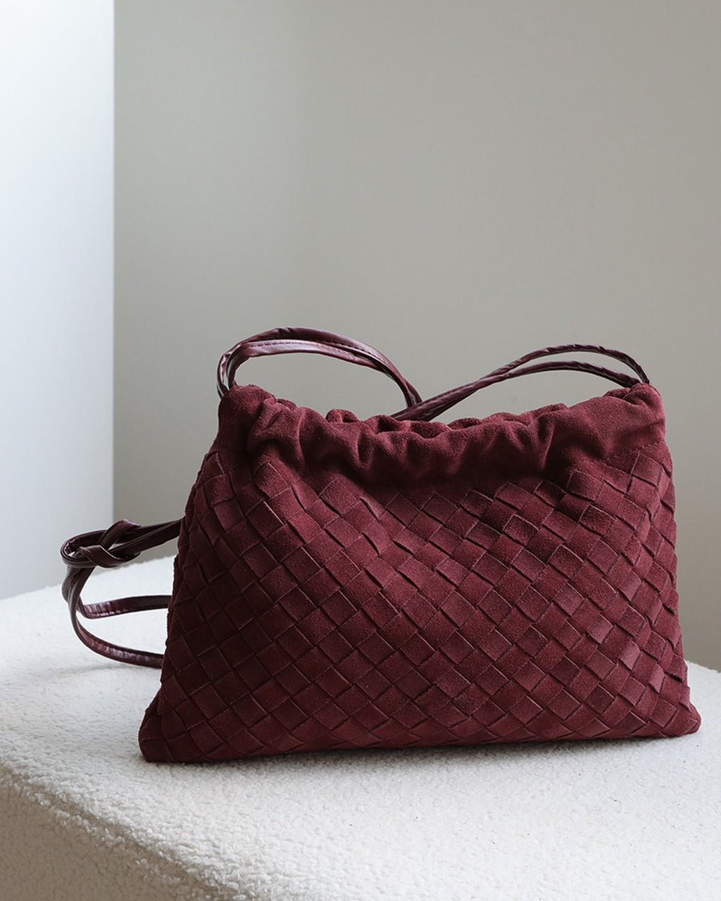 Wildfool The Mantova Drawstring Pouch in Burgundy, on a stone plinth