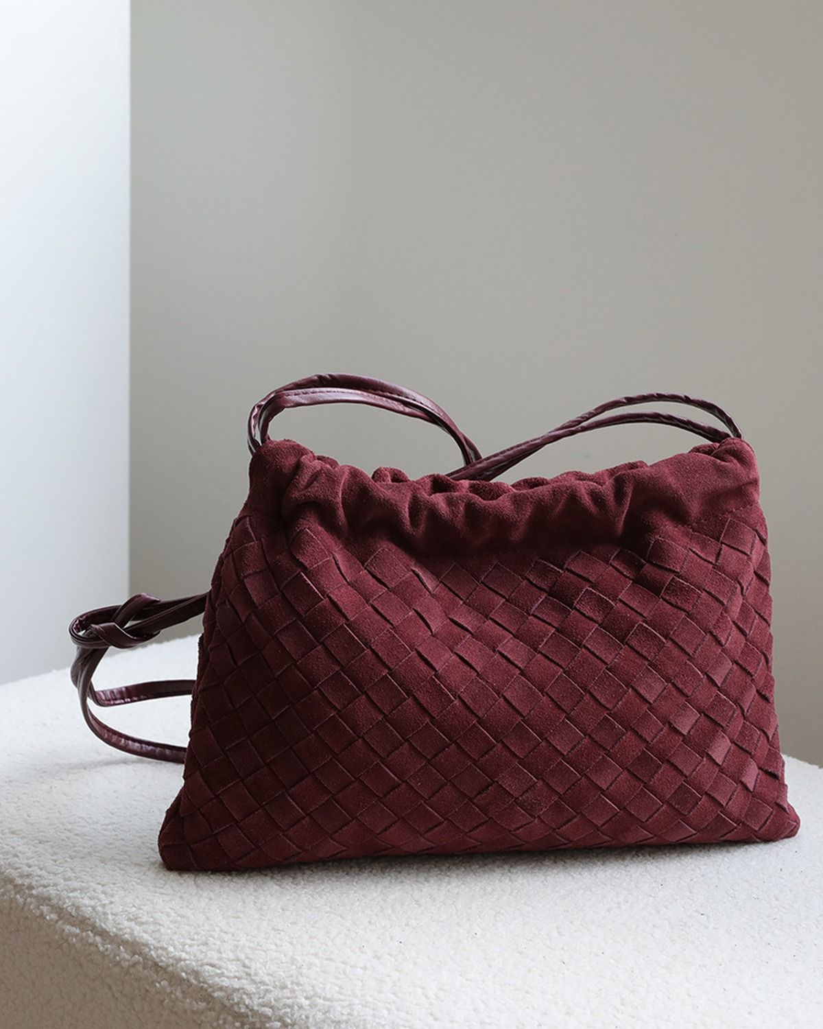 Wildfool The Mantova Drawstring Pouch in Burgundy, on a stone plinth