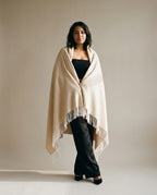 Herringbone cashmere throw draped over the shoulders of a model — lifestyle living room shot