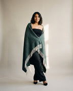 Wildfool herringbone throw in oat draped over a reading chair with an open book