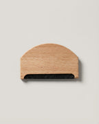 Hand using the beechwood comb to lift pills off a folded cashmere sweater