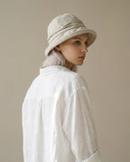 Wildfool structured rolled-brim linen hat in oat — front view on cream linen background
