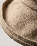Linen hat resting on a café table next to a flat white — lifestyle moment