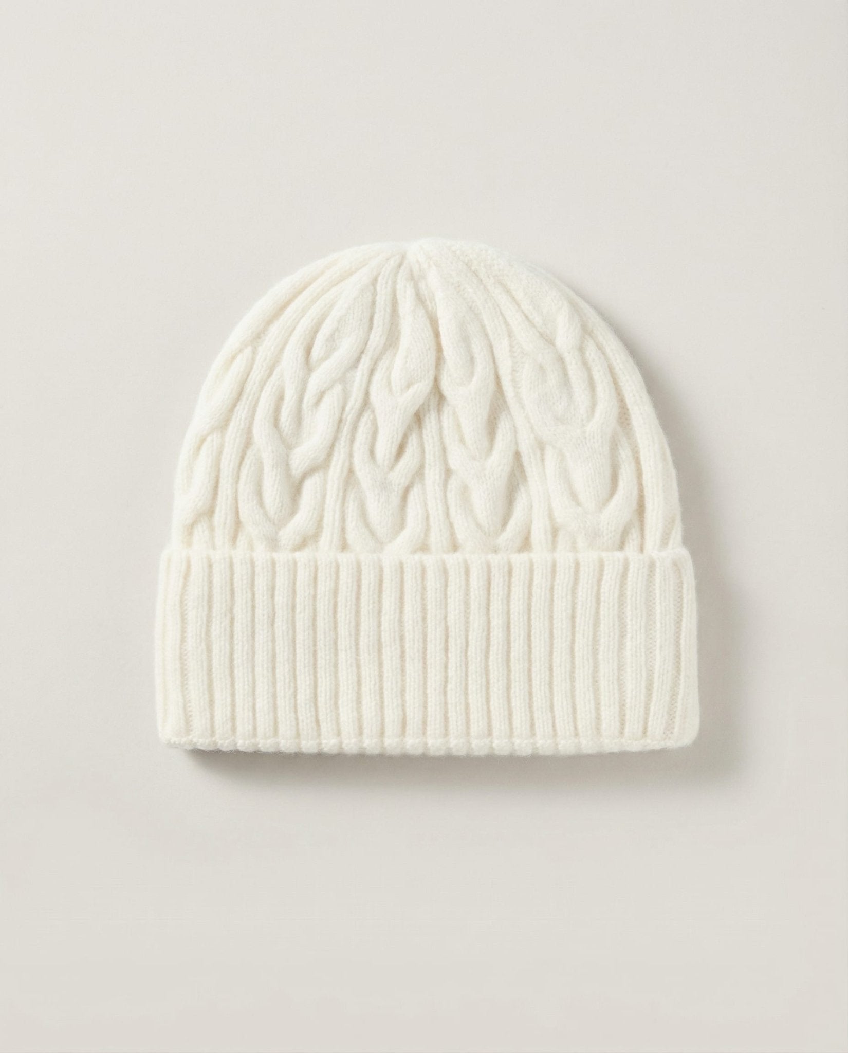 Hand pulling the cable-knit beanie down over the ear — lifestyle motion shot