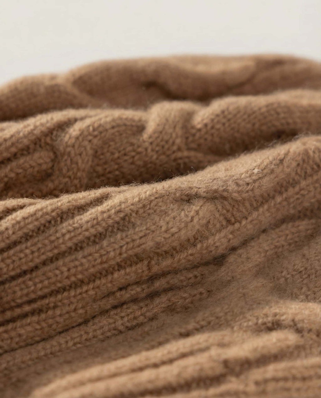 Wildfool cable-knit beanie in cream — alternative front view on weathered wood