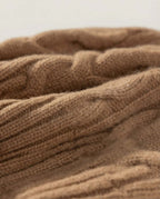 Wildfool cable-knit beanie in cream — alternative front view on weathered wood