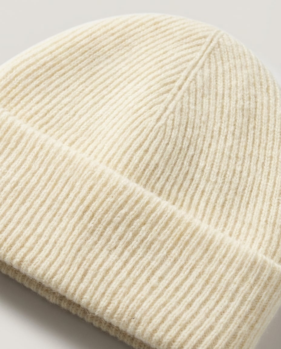 Hand lifting the brim of the cashmere-blend beanie to show the double layer construction