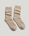 Cashmere bed socks worn on feet tucked into a couch — evening lifestyle shot