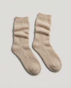 Cashmere bed socks worn on feet tucked into a couch — evening lifestyle shot