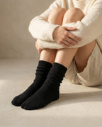 Wildfool cashmere bed socks beside a book and a candle — nightstand still life