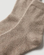 Hand lifting one cashmere bed sock to show the barely-there 40g weight