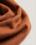 Hand tilting the scarf in light to demonstrate the shifting surface movement