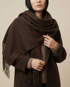 Slim scarf tucked under a trench coat collar — front portrait in city light